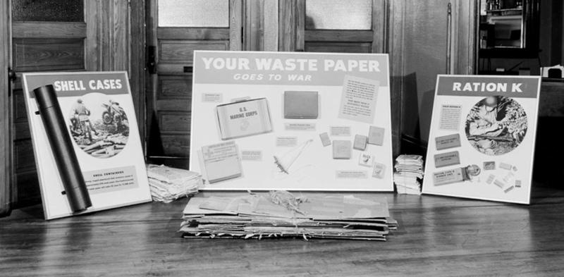 Display boards "Your Waste Paper Goes to War" "Ration K" and "Shell Cases" feature types of packaging made from recycled waste paper, includes field ration boxes, cartons for dried eggs, and shell containers.