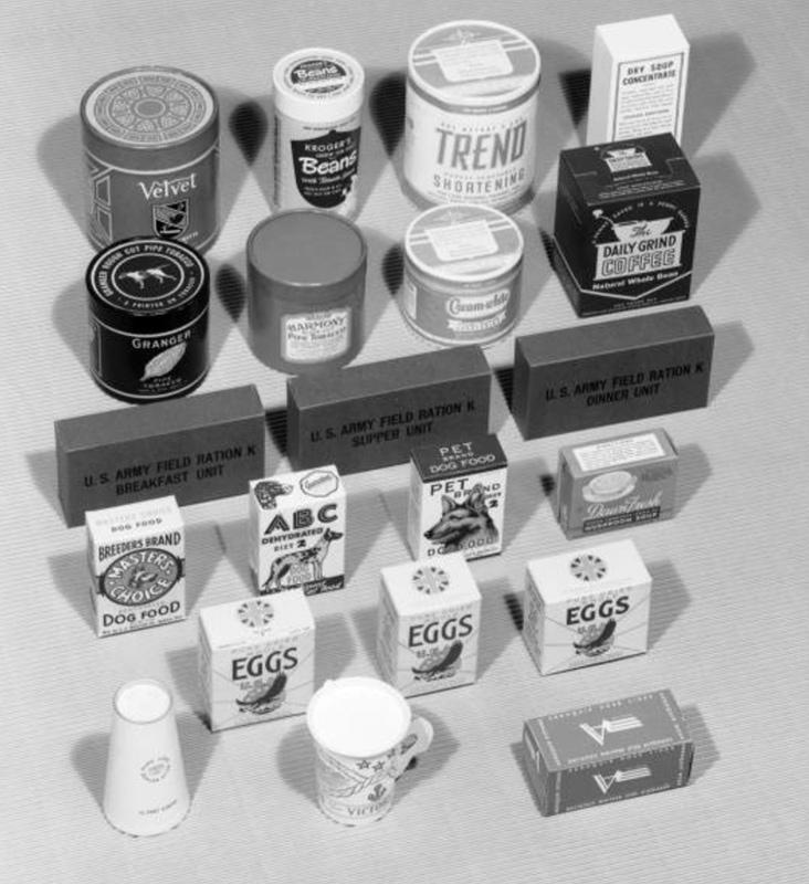 Paper carton display includes Velvet Tobacco, Kroger's Beans, Trend Shortening, Dry Soup Concentrate, Granger Fine Tobacco, Harmony Pipe Tobacco, Cream White Shortening, Daily Grind Coffee, U.S. Army Field Ration K, Breeder's Brand Dog Food, ABC Dehydrated Dog Food, Pet Brand Dog Food, Dawn Fresh Mushroom Soup, Eggs, and Aeroquip Hose Lines.